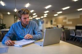 paul college online MBA looking at coursework on his laptop